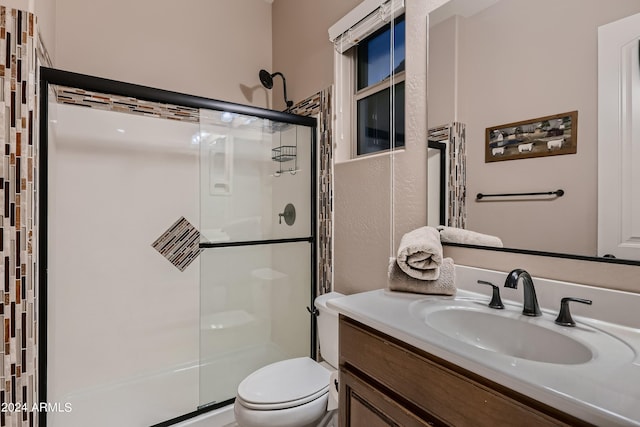 bathroom featuring a shower stall, toilet, and vanity