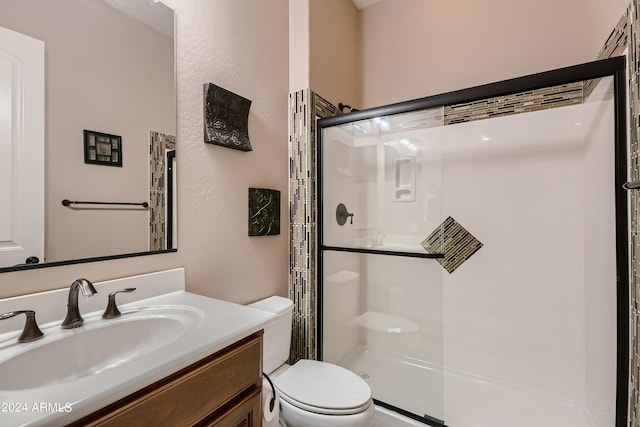 full bathroom featuring vanity, a shower stall, and toilet