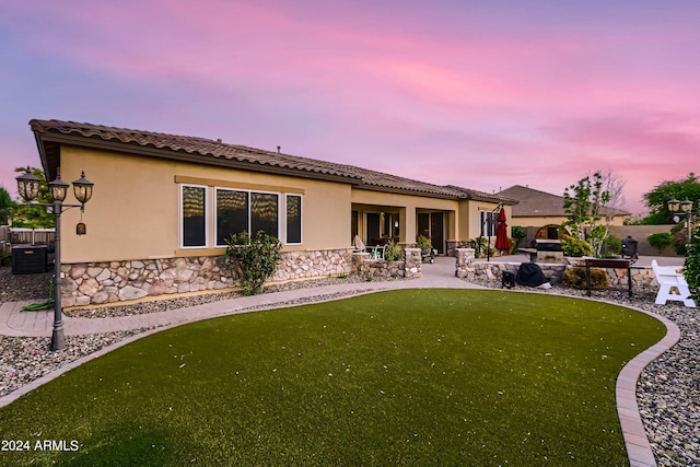 back of house at dusk featuring stucco siding, a tile roof, a patio, and fence