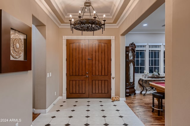 foyer with a notable chandelier, baseboards, a tray ceiling, and ornamental molding