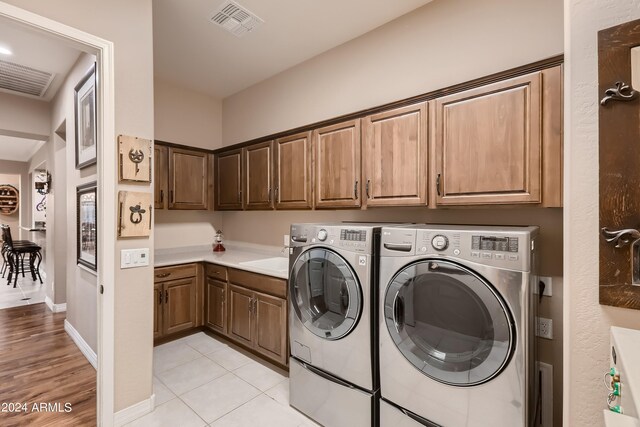 clothes washing area with light tile patterned floors, visible vents, cabinet space, and separate washer and dryer