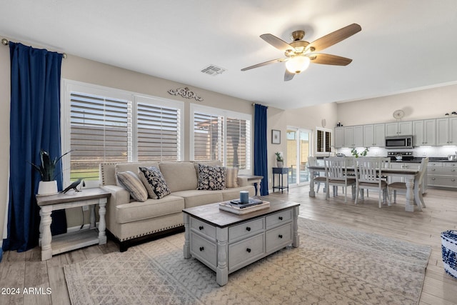 living room with light hardwood / wood-style flooring and ceiling fan