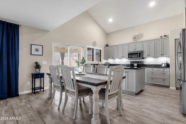 dining space featuring light hardwood / wood-style flooring and high vaulted ceiling