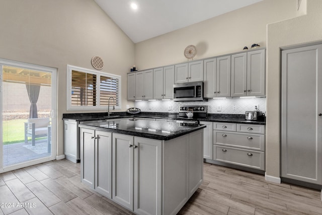 kitchen with a center island, high vaulted ceiling, light hardwood / wood-style flooring, and appliances with stainless steel finishes