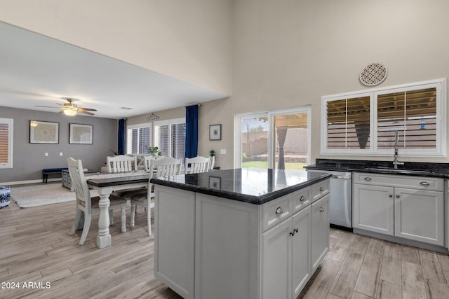 kitchen with dishwasher, a center island, white cabinets, sink, and light wood-type flooring