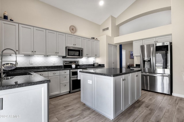 kitchen featuring sink, a center island, light hardwood / wood-style floors, decorative backsplash, and appliances with stainless steel finishes