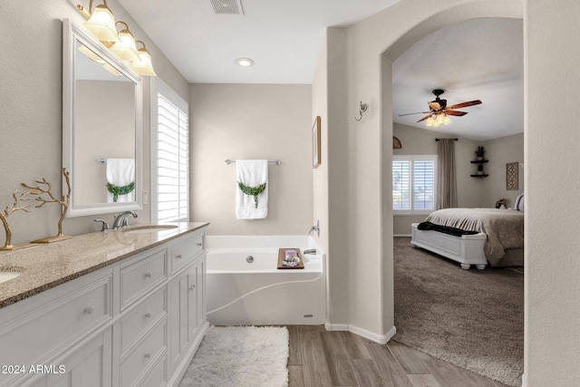 bathroom featuring plenty of natural light, ceiling fan, wood-type flooring, and a washtub