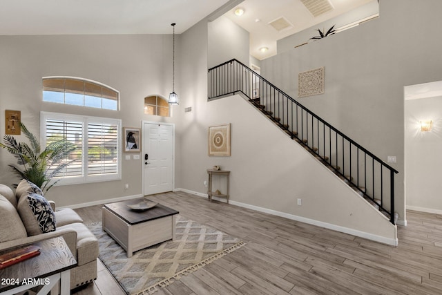 living room featuring high vaulted ceiling and light hardwood / wood-style flooring