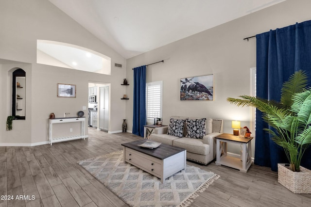 living room featuring high vaulted ceiling and light wood-type flooring