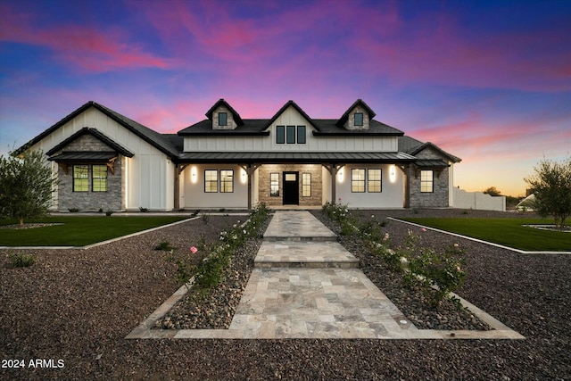 modern inspired farmhouse featuring a standing seam roof, stone siding, metal roof, and covered porch