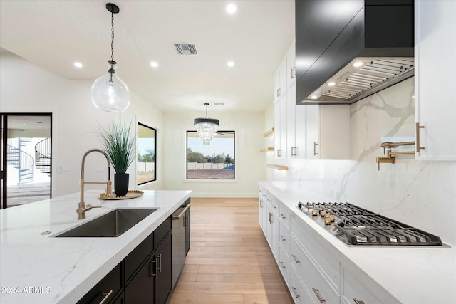 kitchen featuring stainless steel appliances, a sink, visible vents, dark cabinetry, and custom range hood