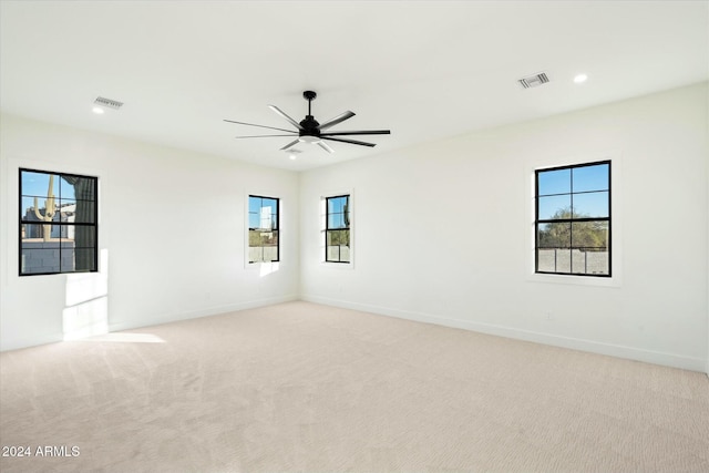 spare room with light carpet, a healthy amount of sunlight, and visible vents