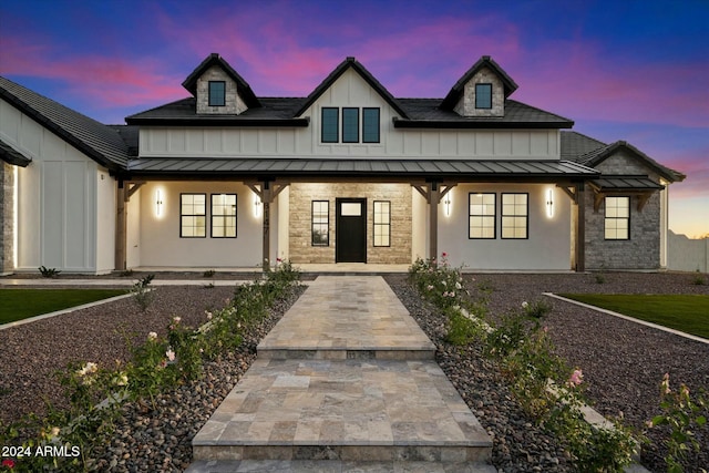 modern farmhouse style home featuring metal roof, stone siding, and a standing seam roof