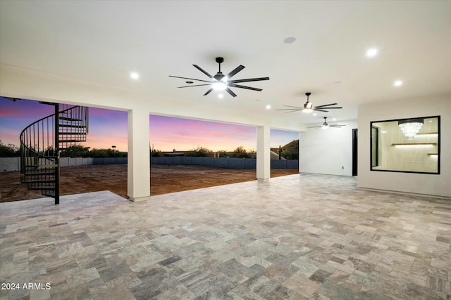 patio terrace at dusk with ceiling fan, fence, and stairway