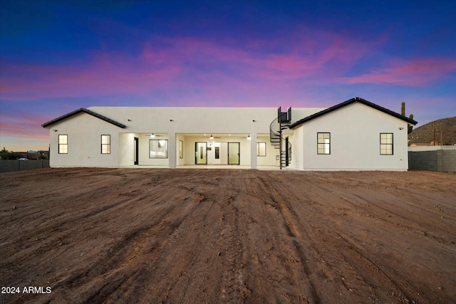 view of front of house with ceiling fan, fence, and stucco siding