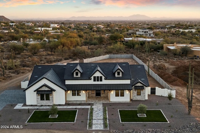 view of front of property featuring stone siding, covered porch, fence, and stucco siding