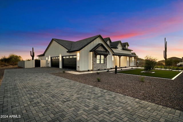 modern farmhouse featuring a garage, decorative driveway, and board and batten siding