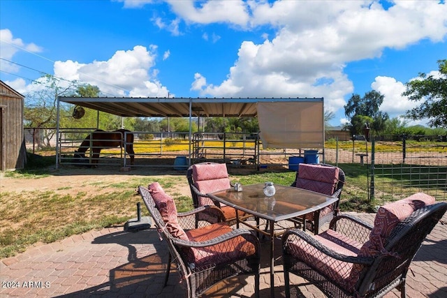 view of patio with an exterior structure, outdoor dining area, and an outbuilding