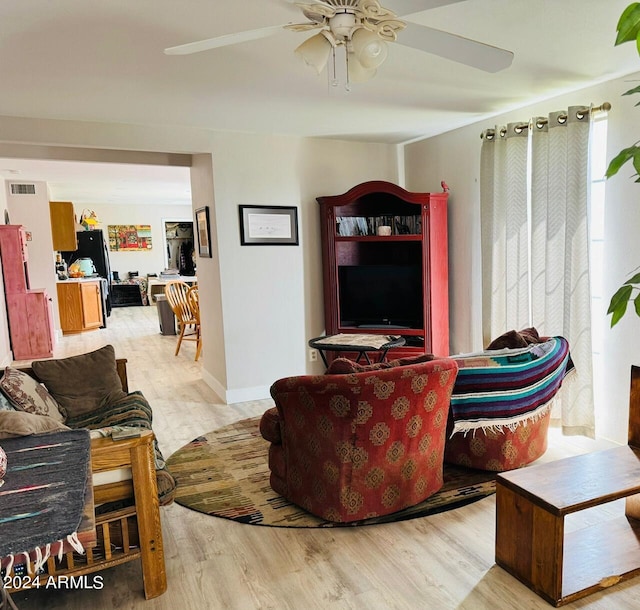 living room featuring visible vents, light wood-style flooring, and ceiling fan