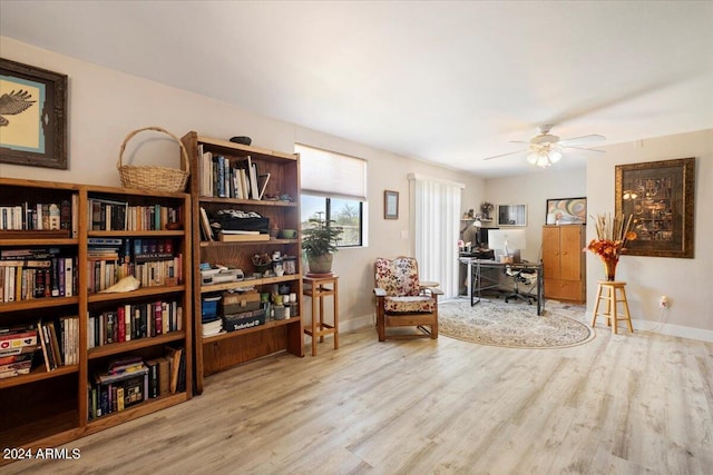 living area featuring a ceiling fan, baseboards, and wood finished floors