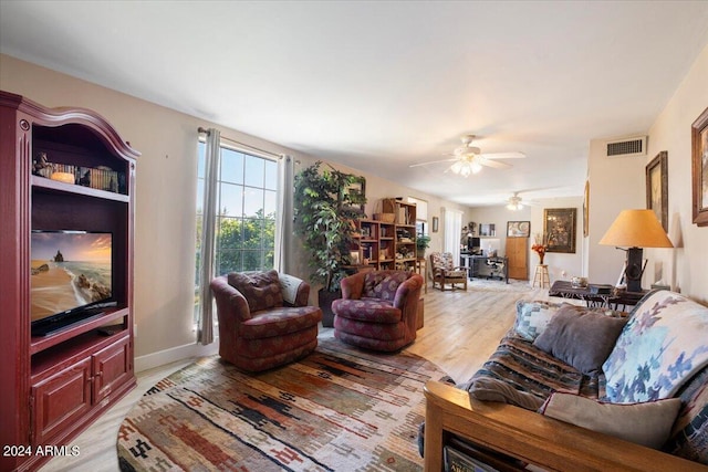 living area with visible vents, light wood-style flooring, baseboards, and a ceiling fan