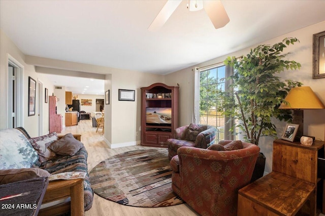 living area with baseboards, light wood-style floors, and ceiling fan