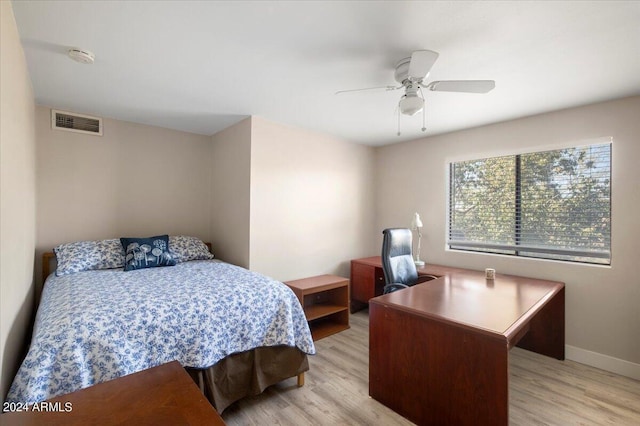 bedroom featuring light wood-style flooring, a ceiling fan, visible vents, and baseboards