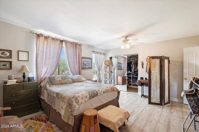 bedroom featuring baseboards, a closet, light wood finished floors, and ceiling fan