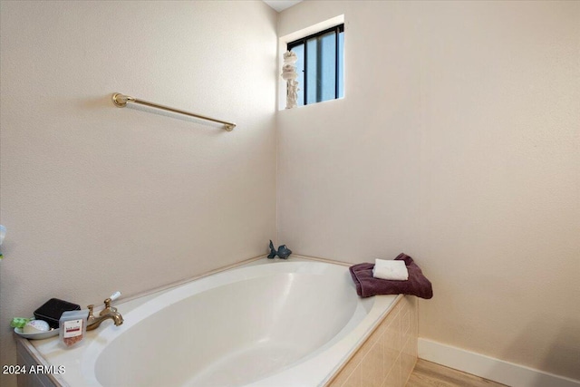 full bathroom featuring baseboards, a garden tub, and wood finished floors