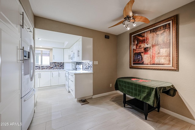 kitchen featuring ceiling fan, tasteful backsplash, white appliances, white cabinets, and sink