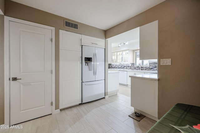 kitchen featuring white appliances, white cabinetry, tasteful backsplash, sink, and rail lighting