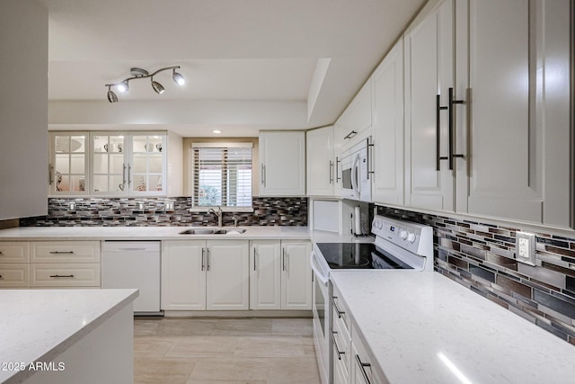 kitchen featuring decorative backsplash, white appliances, white cabinets, light stone counters, and sink