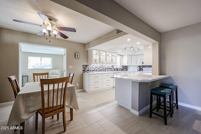 kitchen featuring a breakfast bar, kitchen peninsula, decorative backsplash, white cabinets, and range