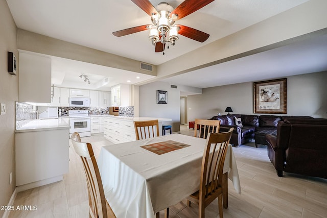 dining space featuring ceiling fan and a raised ceiling