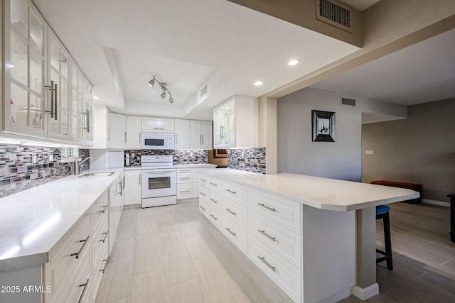 kitchen with a kitchen island, sink, white appliances, a kitchen breakfast bar, and white cabinets