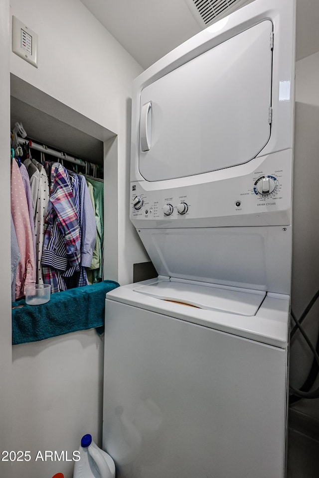 clothes washing area featuring stacked washing maching and dryer