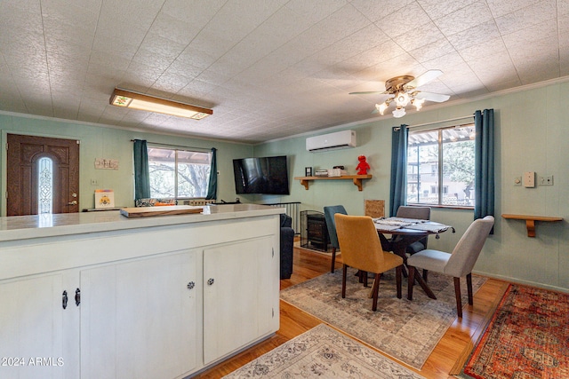 kitchen featuring white cabinets, a wealth of natural light, light hardwood / wood-style floors, and a wall mounted AC