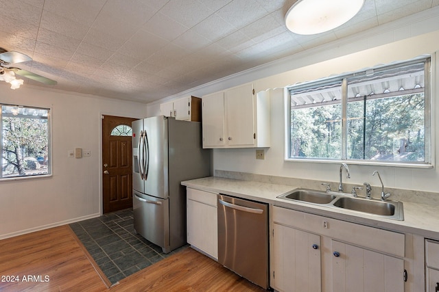 kitchen featuring dark wood-type flooring, a sink, white cabinets, light countertops, and appliances with stainless steel finishes