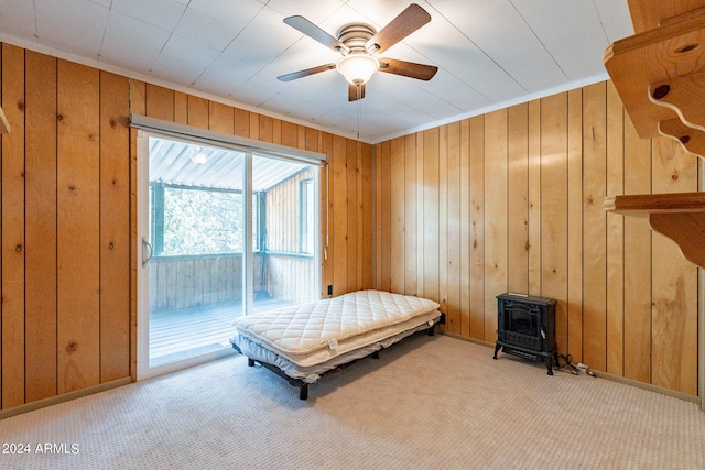 bedroom with ceiling fan, wooden walls, access to exterior, and light colored carpet