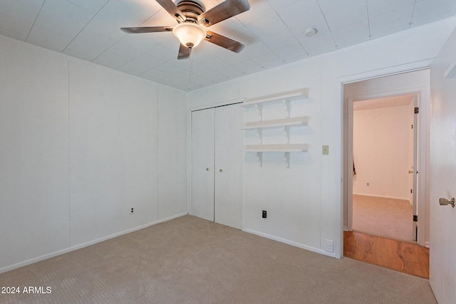 unfurnished bedroom featuring a ceiling fan, a closet, and light colored carpet