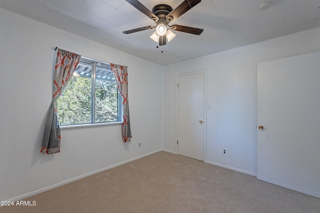 empty room featuring light colored carpet, ceiling fan, and baseboards