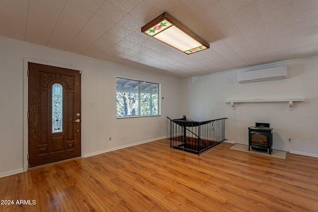 entryway with a wood stove, a wall unit AC, baseboards, and light wood finished floors