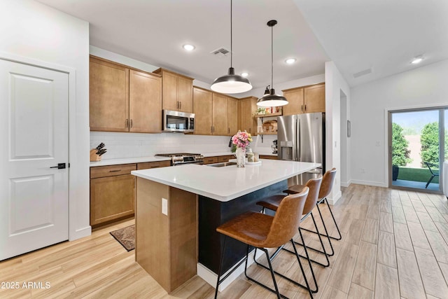 27510 N 30th Ln, Phoenix, AZ 85083 - kitchen with appliances with stainless steel finishes, light wood-type flooring, decorative backsplash, a kitchen bar, and pendant lighting