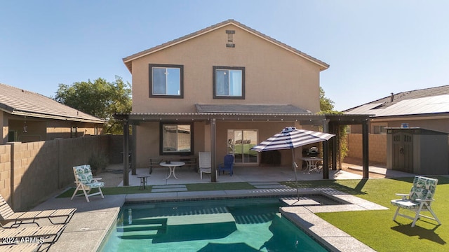 back of house featuring a storage unit, a fenced in pool, and a patio