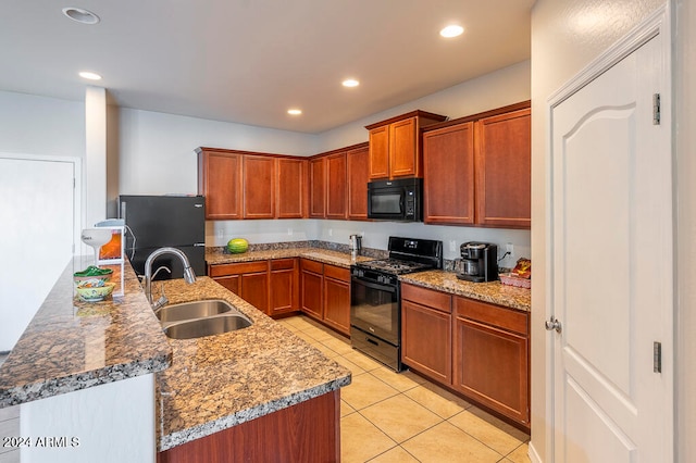 kitchen with light tile patterned floors, stone counters, sink, and black appliances