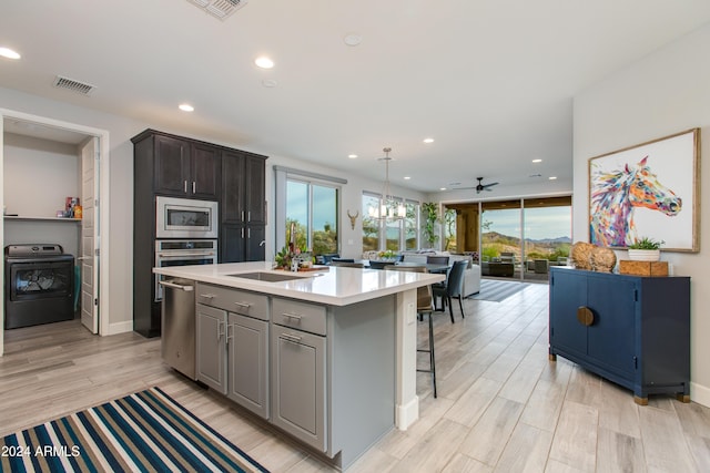 kitchen featuring a center island, ceiling fan, light hardwood / wood-style floors, stainless steel appliances, and washer / clothes dryer