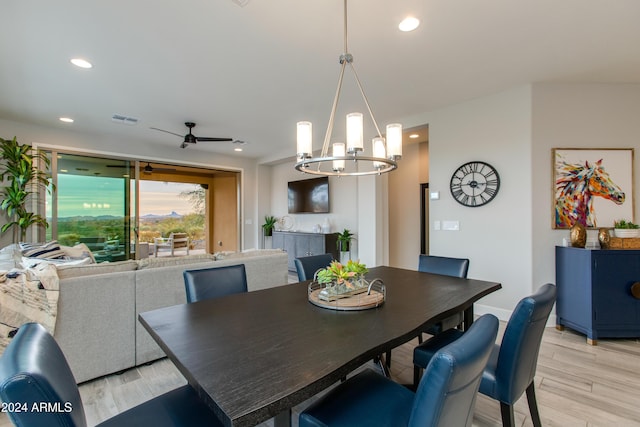 dining space featuring ceiling fan with notable chandelier and light wood-type flooring