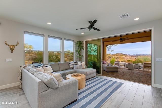 living room with a mountain view, ceiling fan, and light hardwood / wood-style floors