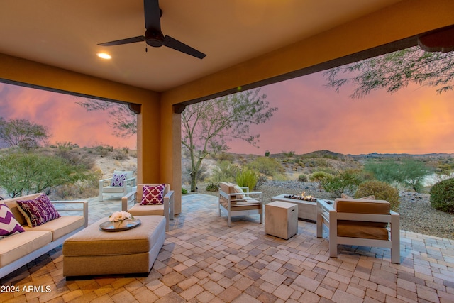 patio terrace at dusk with ceiling fan and an outdoor living space with a fire pit