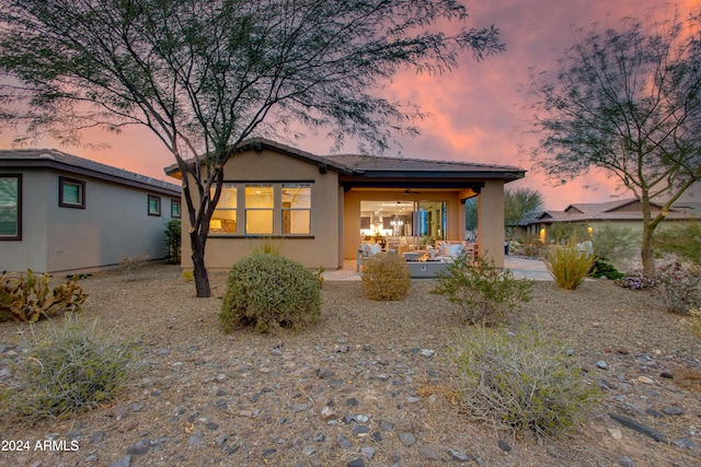 back house at dusk featuring a patio